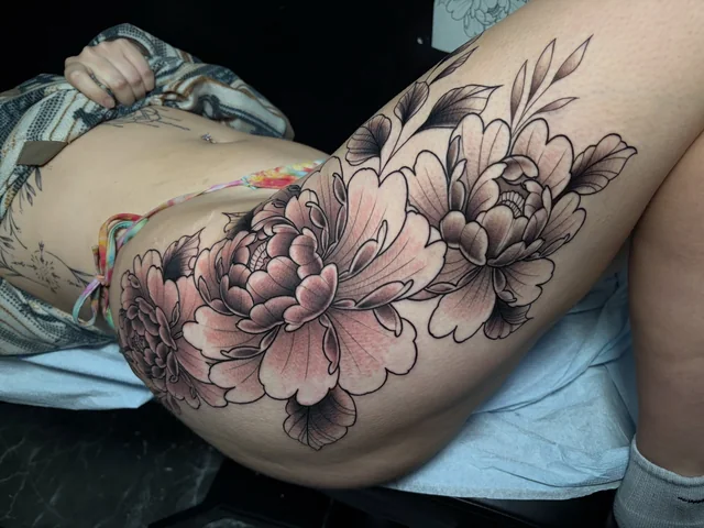 Wide view of a black and grey floral composition across a thigh.
