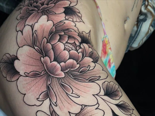 Closer view of shaded petals and leaves in the same floral thigh tattoo.