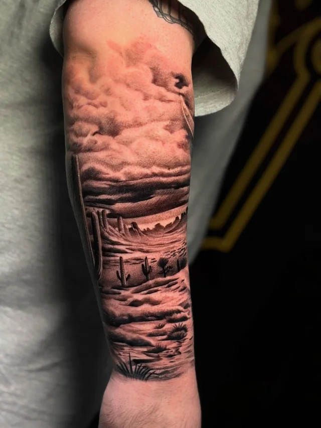 Lighthouse above a rocky shore and waves in a black and grey arm tattoo.
