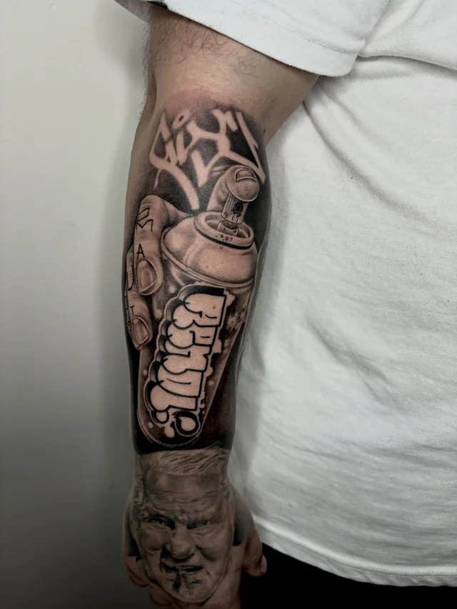 Mechanical and skeletal figure forms in a detailed black and grey upper-arm tattoo.