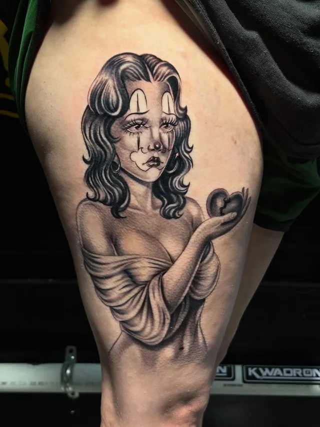 Black and grey female portrait with facial ornament and a dark heart shape on an upper arm.