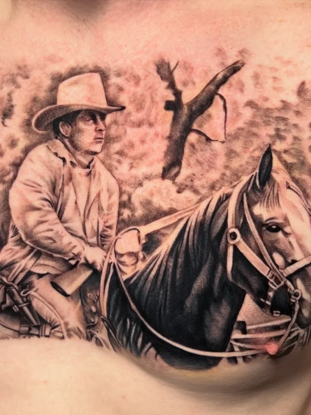 Black and grey rider on a horse with birds and branches in a broad torso tattoo.
