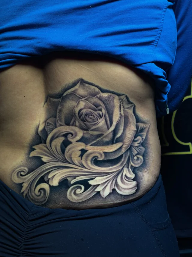 Black and grey rose with curling leaves and ornamental scrollwork on the side of the body.