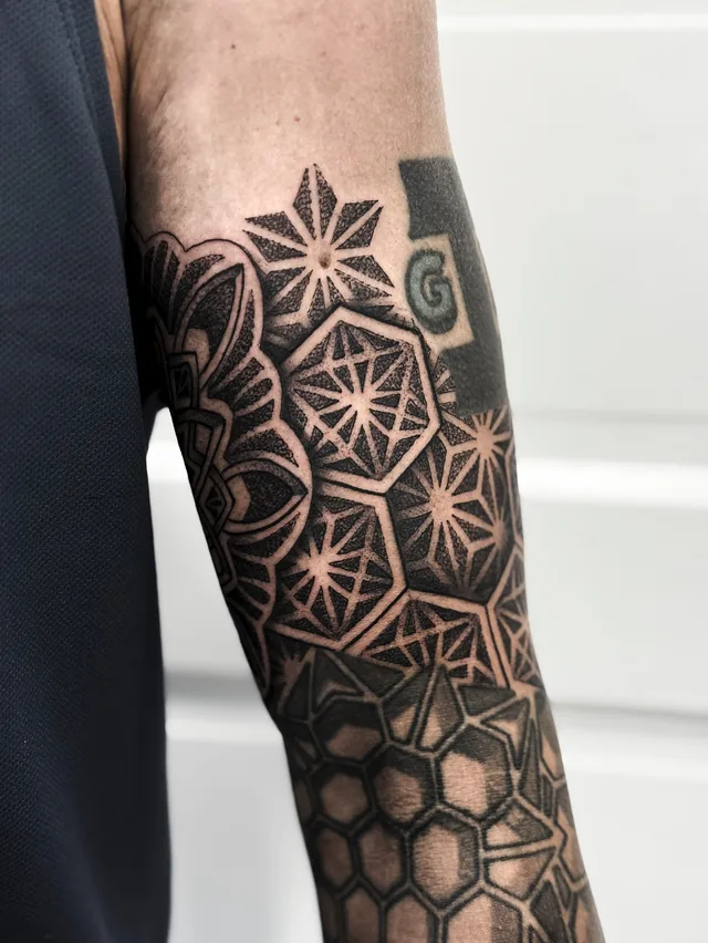 Side view of the same arm area with small starburst panels, hexagons and a honeycomb-like grid.