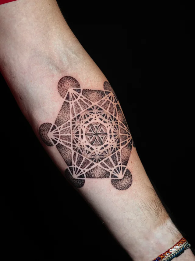 Wider view of the same interlocking circle-and-polygon tattoo on the forearm.