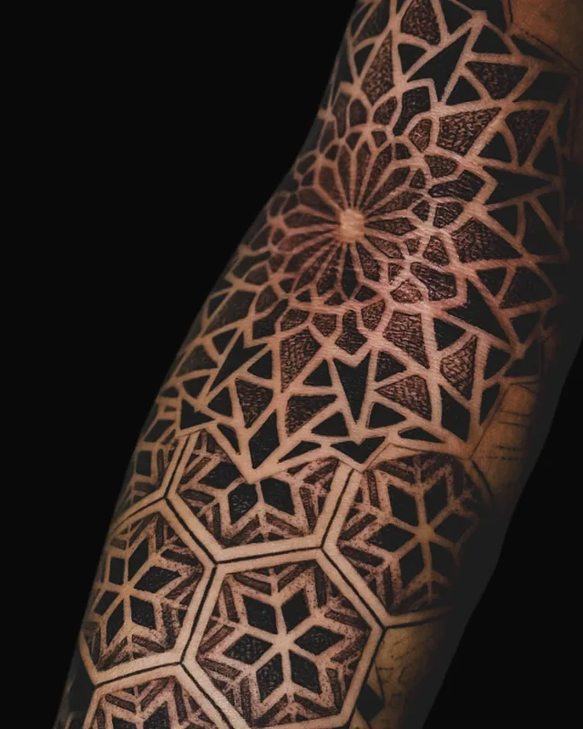 Close angled view of the rosette and hexagonal panels in the same geometric forearm tattoo.