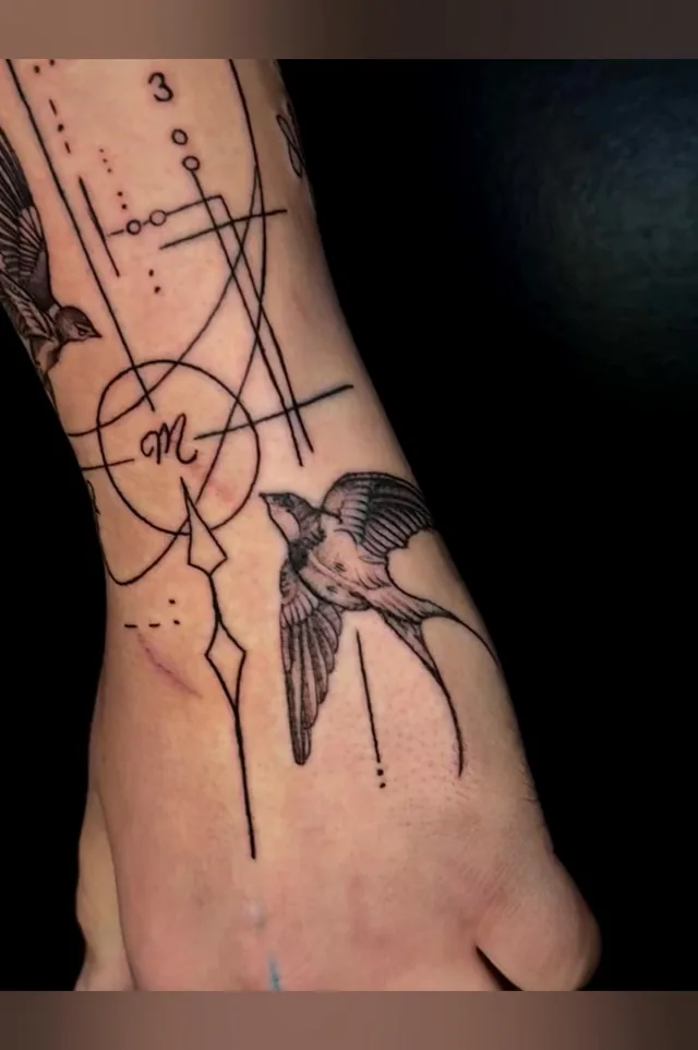 Close view of a bird and intersecting line-and-circle details near the wrist in the same tattoo.