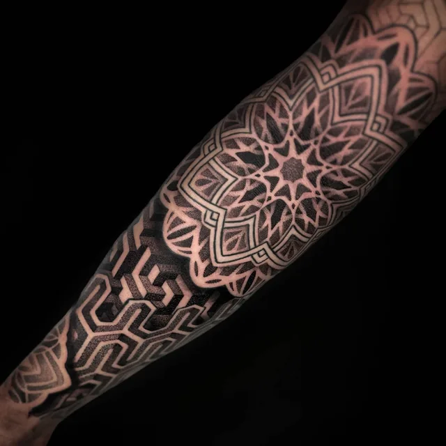 Angled forearm view showing the same framed mandala beside interlocking geometric patterns.