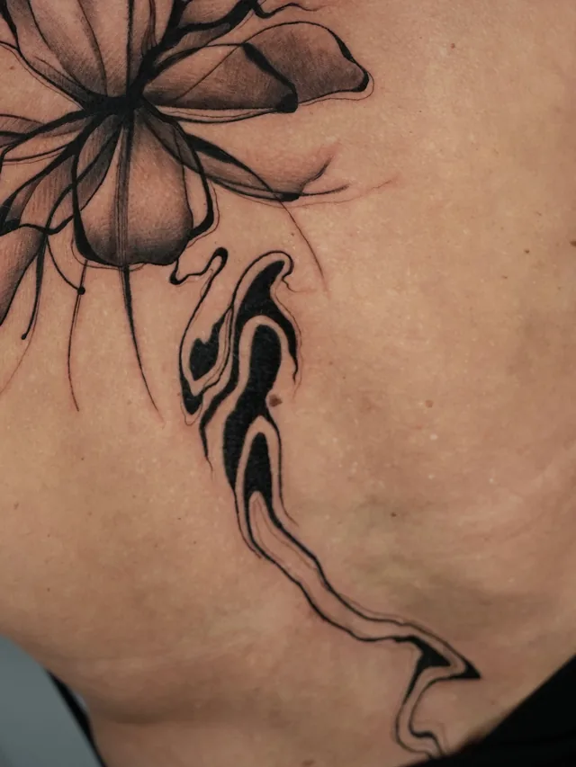 Detail of the flower petals and curving dark ornament in the same back tattoo.
