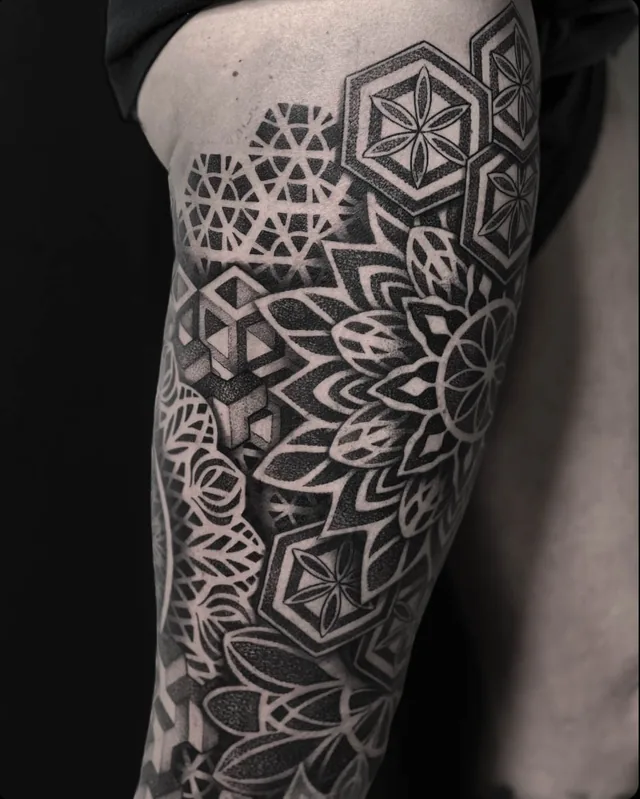 Upper-arm geometric tattoo with hexagonal flower panels, interlocking cubes and a large petal rosette.