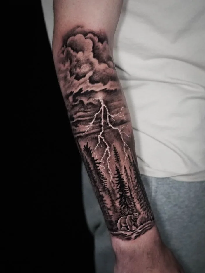 A black-and-gray forearm landscape with tall pine trees, storm clouds, and a bright fork of lightning.