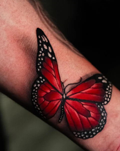 Side angle of the red butterfly on the inner forearm. Artwork by William Martz.