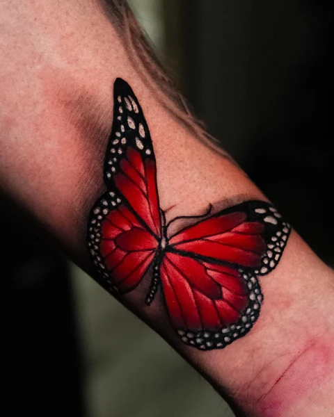 Angled wrist view of the red butterfly tattoo. Artwork by William Martz.