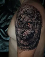 Shoulder angle of the roaring lion tattoo with its orange eye and patterned forehead. Artwork by William Martz.