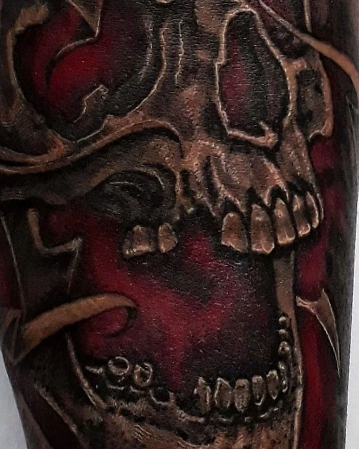 A skull tattoo with rich red areas inside and around the open mouth.