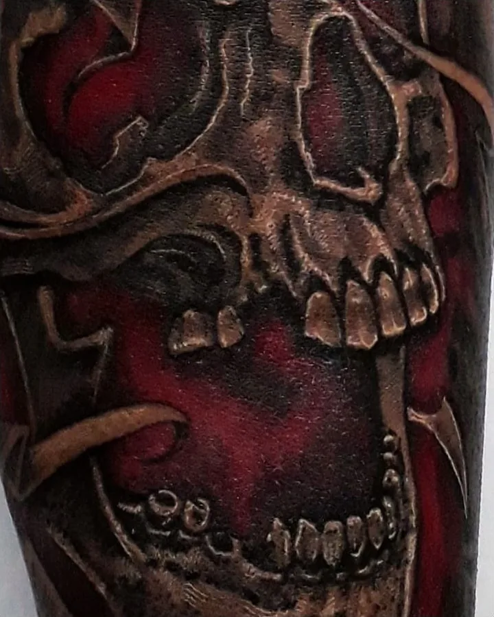 A skull tattoo with rich red areas inside and around the open mouth.