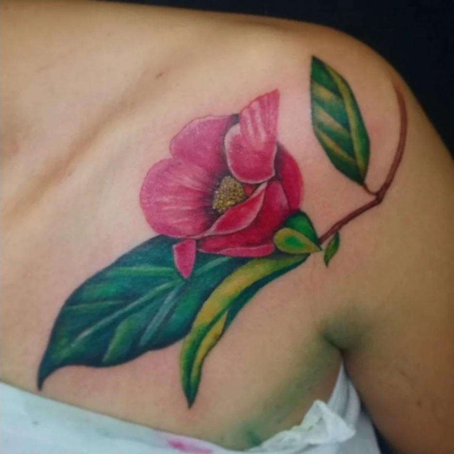 A colorful orchid tattoo with pink petals, green leaves, and a fine curved stem.