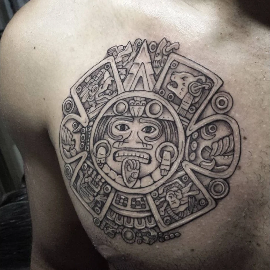 A circular Aztec-inspired sun motif tattoo in black and gray.
