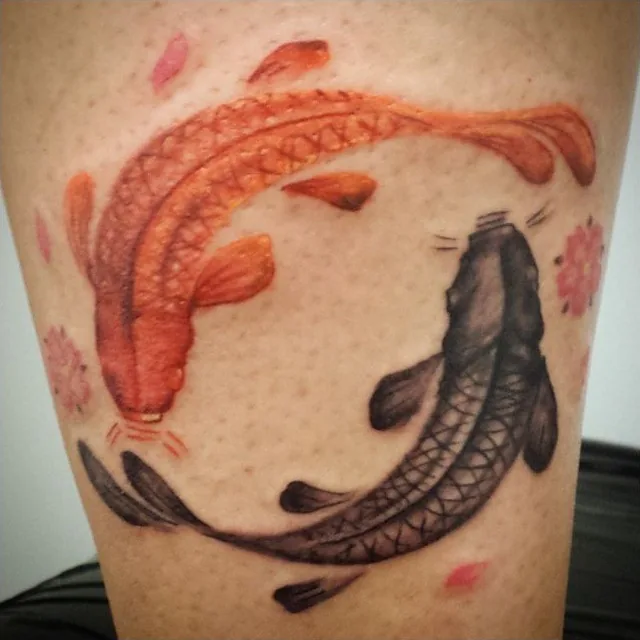 Two koi fish curve toward one another in a circular tattoo composition.
