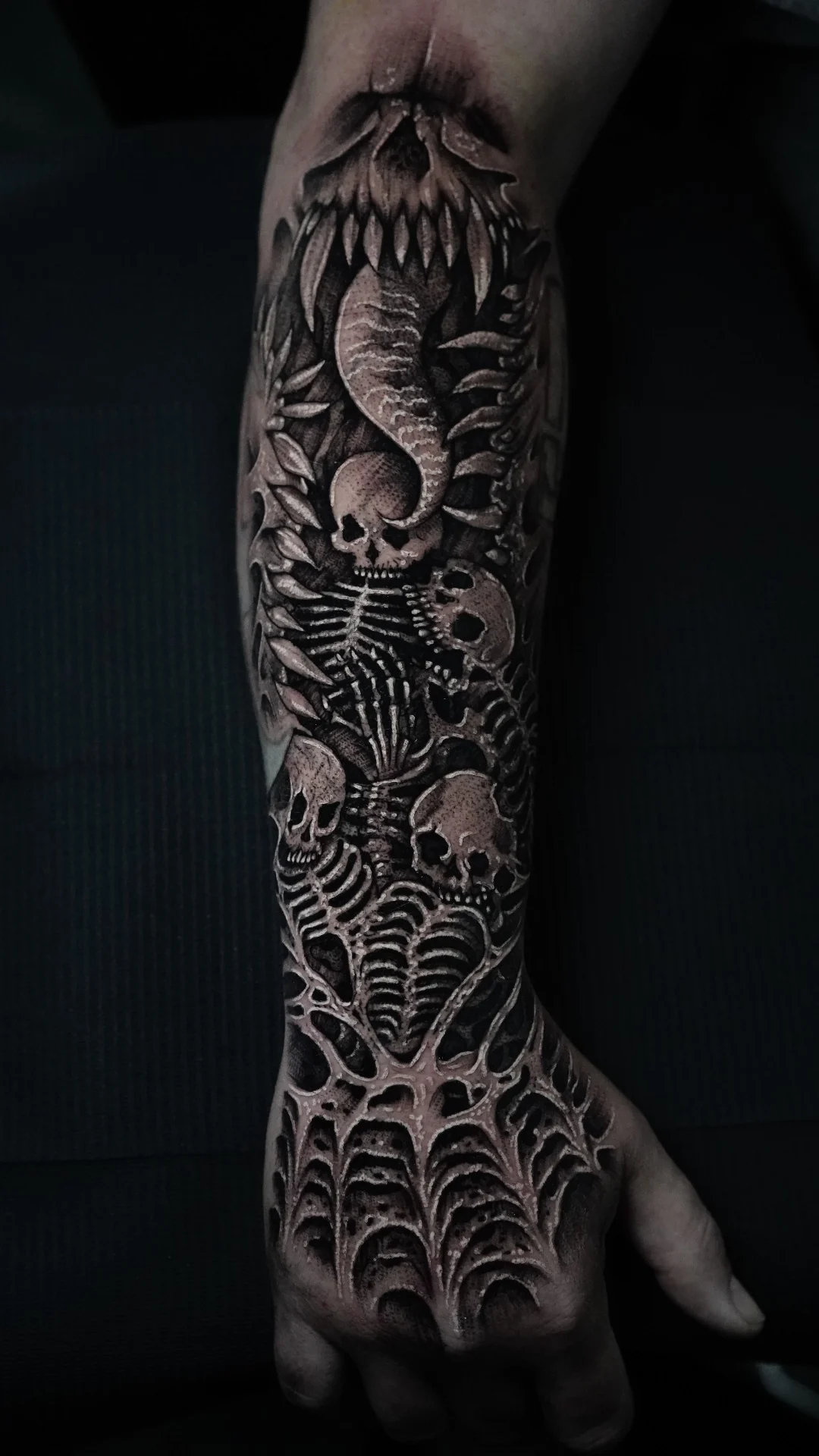 A black-and-gray ornamental composition extending along the forearm and onto the hand.
