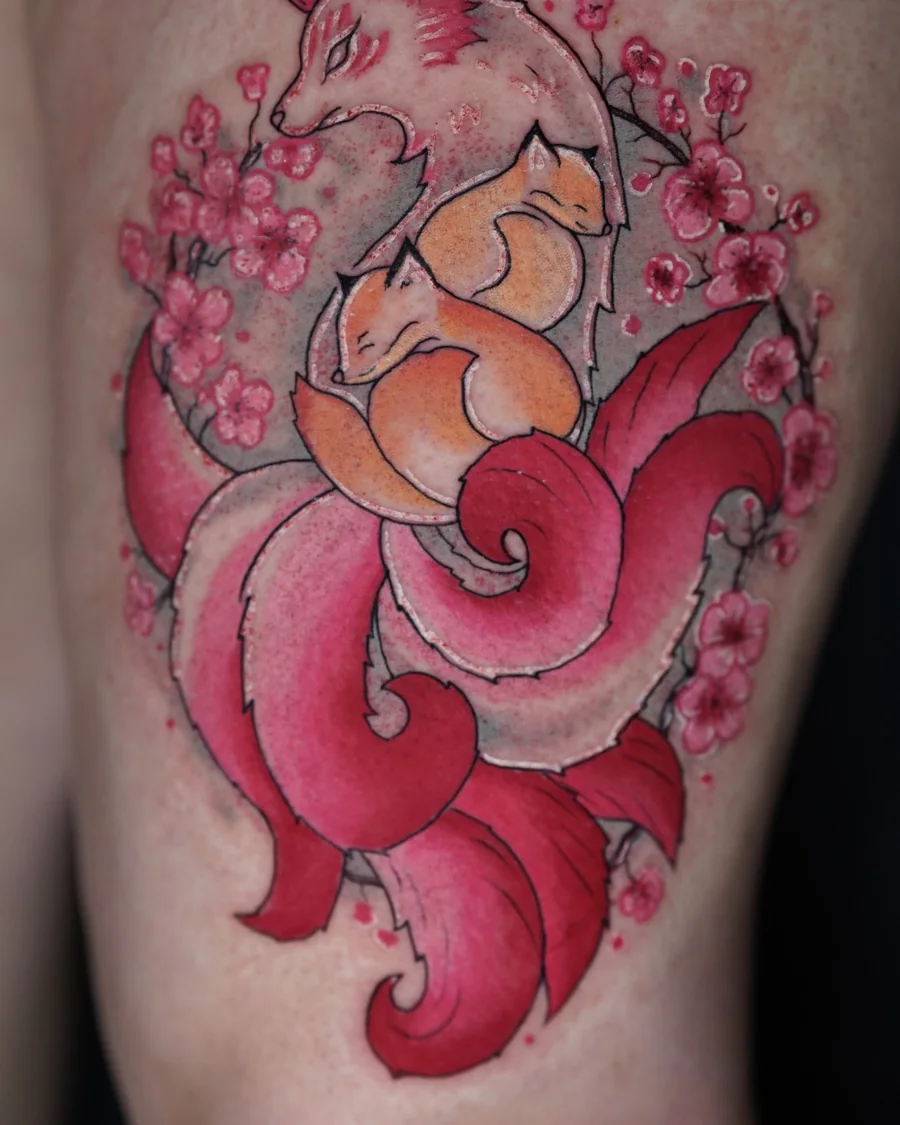 An orange fox tattoo surrounded by red flowing shapes and small blossoms.