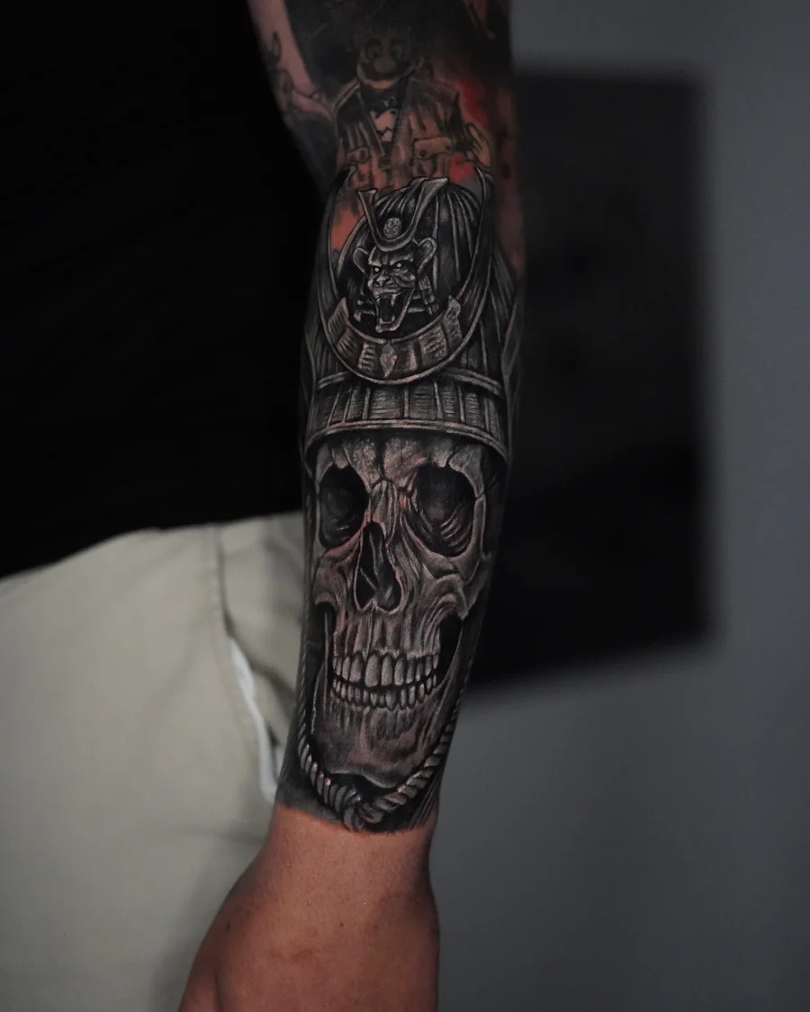 Alternate view. A realistic skull in a samurai helmet tattooed along the forearm, with a round crest above the brow.