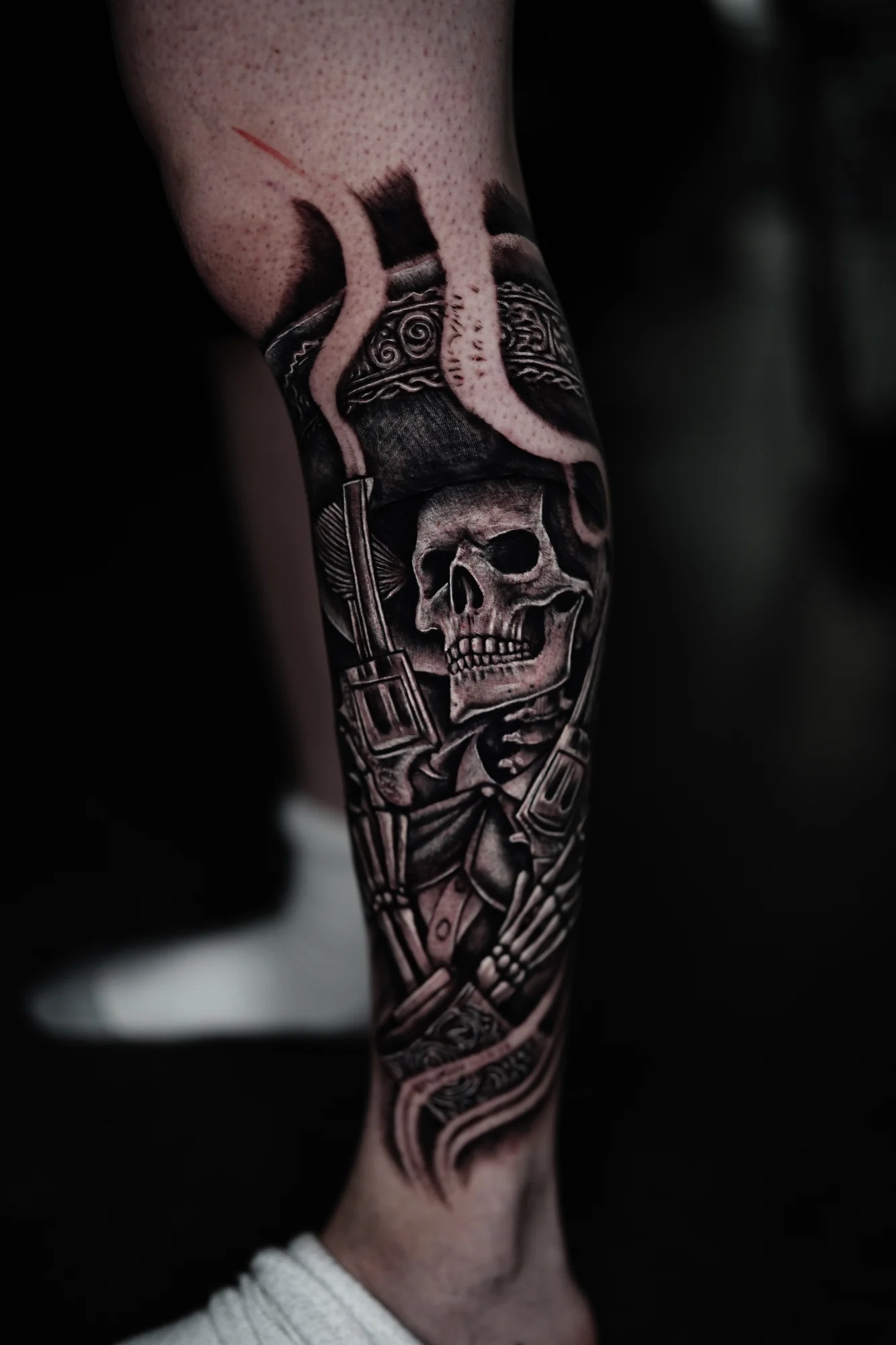 A black-and-gray forearm tattoo of a skull warrior wearing an ornate horned samurai helmet and armor.