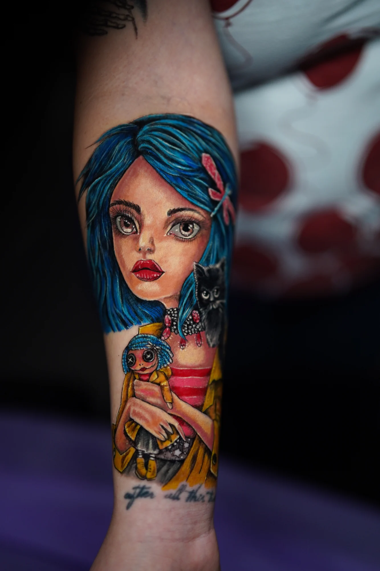 A colorful tattoo of a large-eyed girl with turquoise hair holding a small doll against her chest.