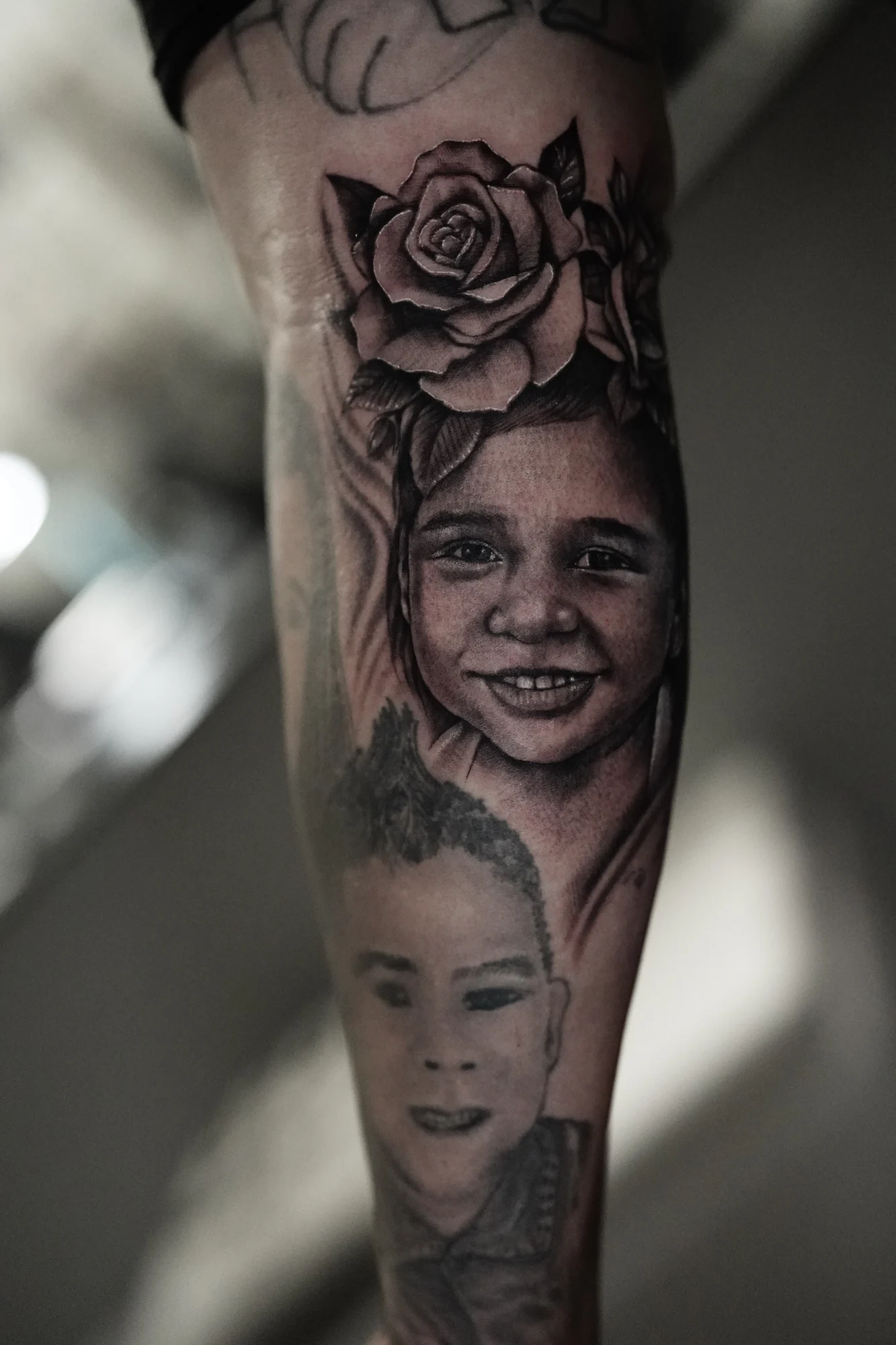 Two realistic human portraits arranged along an arm with a shaded rose between the surrounding details.