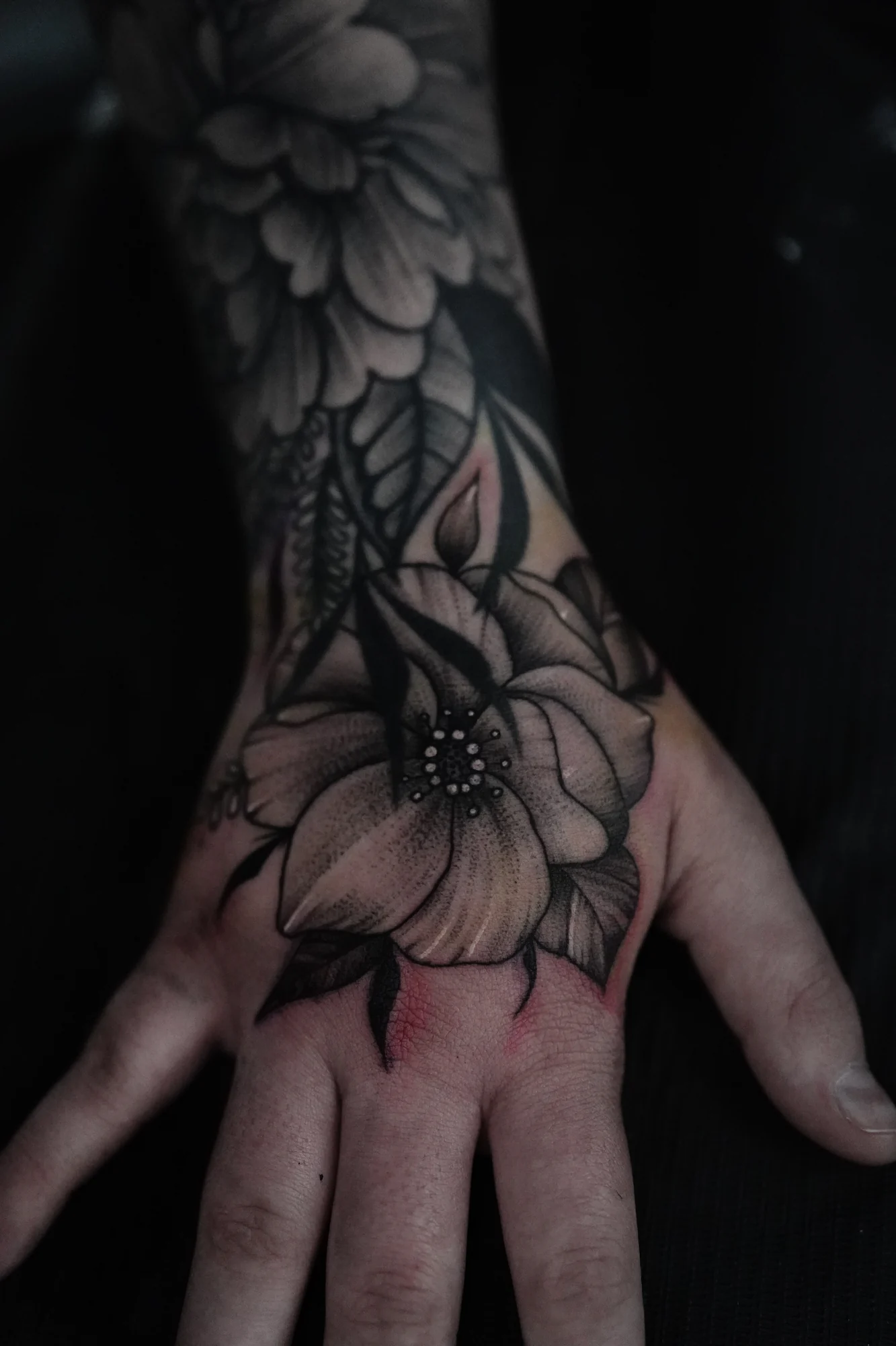 Large shaded flowers and pointed leaves extending from the wrist across the back of the hand.