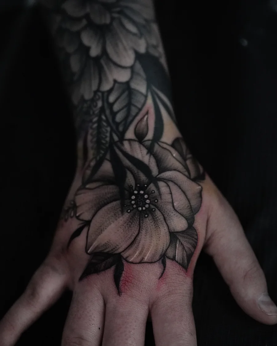 Large shaded flowers and pointed leaves extending from the wrist across the back of the hand.