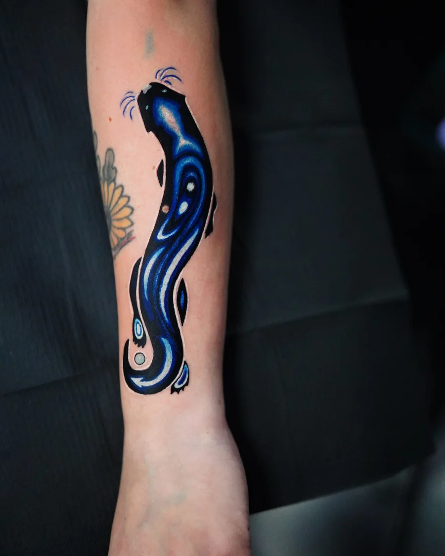 A flowing abstract blue and black tattoo with white highlights running down the forearm.