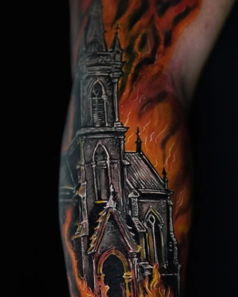A tall church with a pointed steeple surrounded by orange flames in a vertical color tattoo.