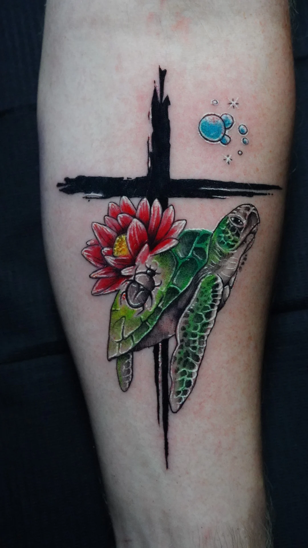 A green sea turtle and red flower beside a dark brushstroke cross, with small blue bubbles above.