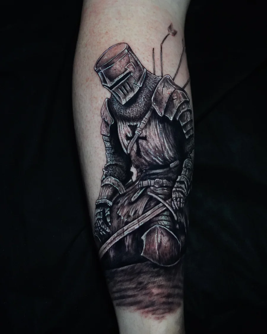A kneeling armored knight with a closed helmet and sword, tattooed in black and gray on the forearm.