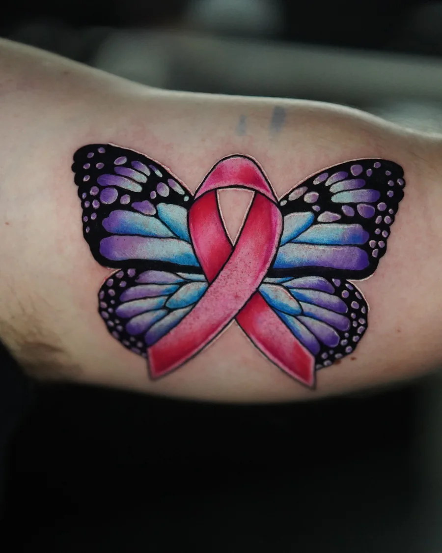 A butterfly with purple and blue wings surrounding a pink ribbon in a color tattoo.