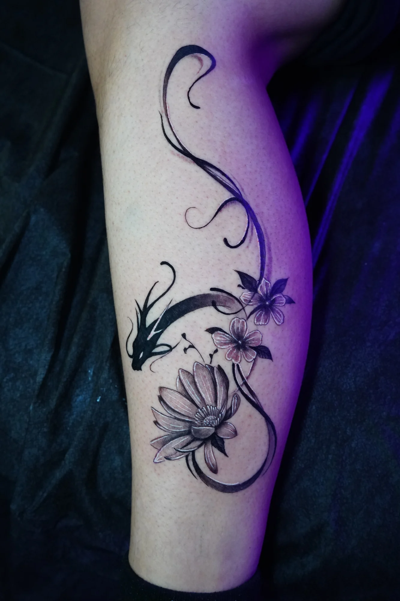 A slender floral vine with shaded blossoms and sweeping curved stems along the arm.
