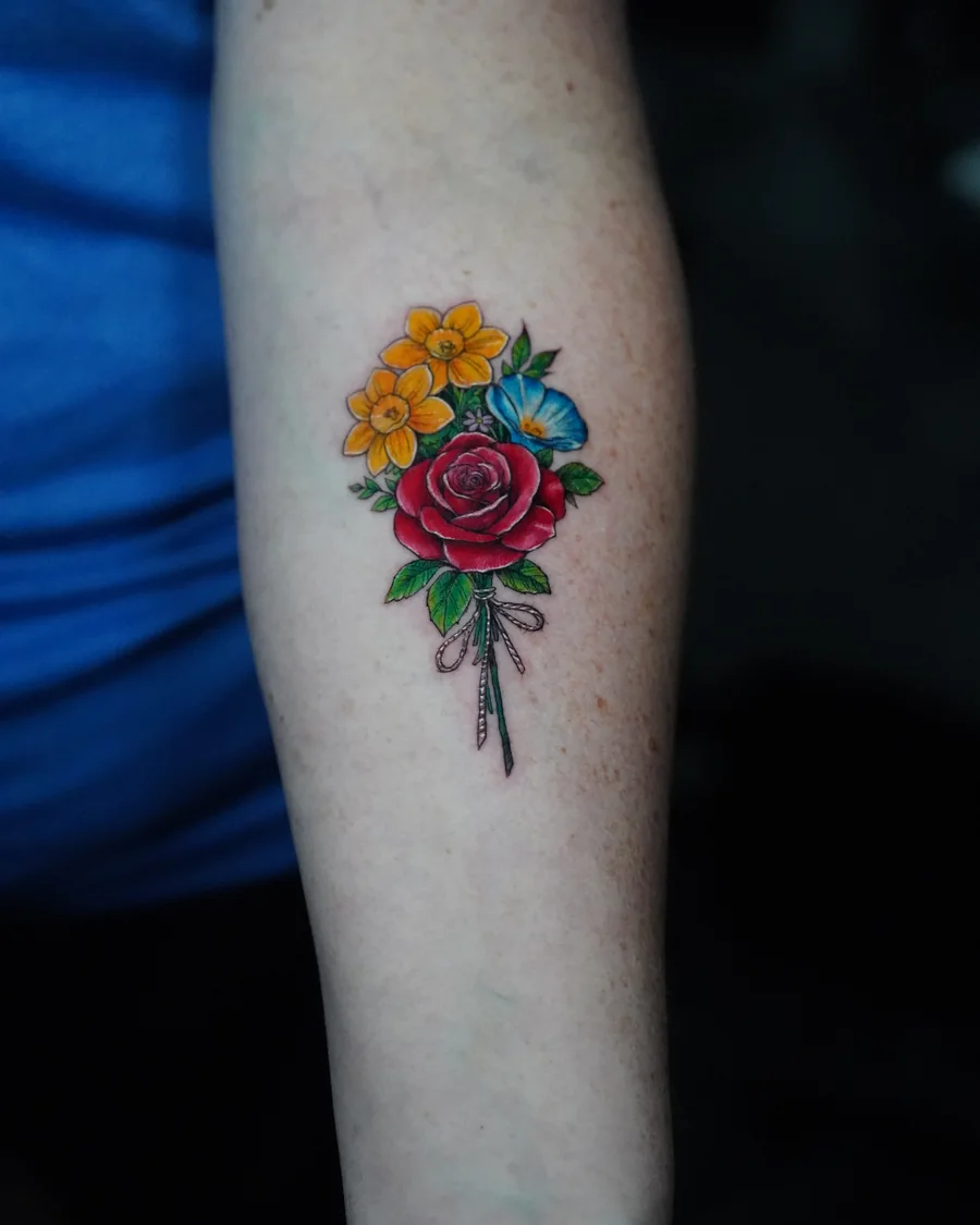 Alternate view. A small colorful bouquet of yellow, red and blue flowers with slender stems on the forearm.