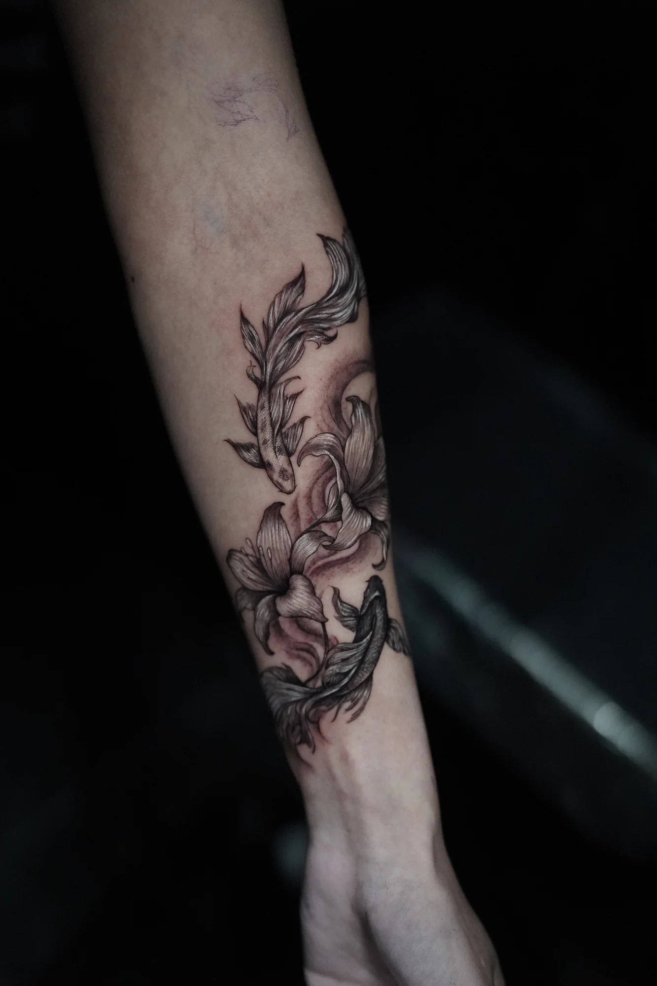 Large shaded blossoms and long flowing leaves arranged down the forearm in black and gray.