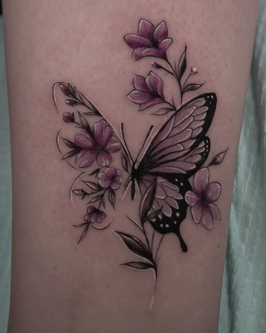 A pink and purple butterfly beside delicate purple flowers and fine black stems.