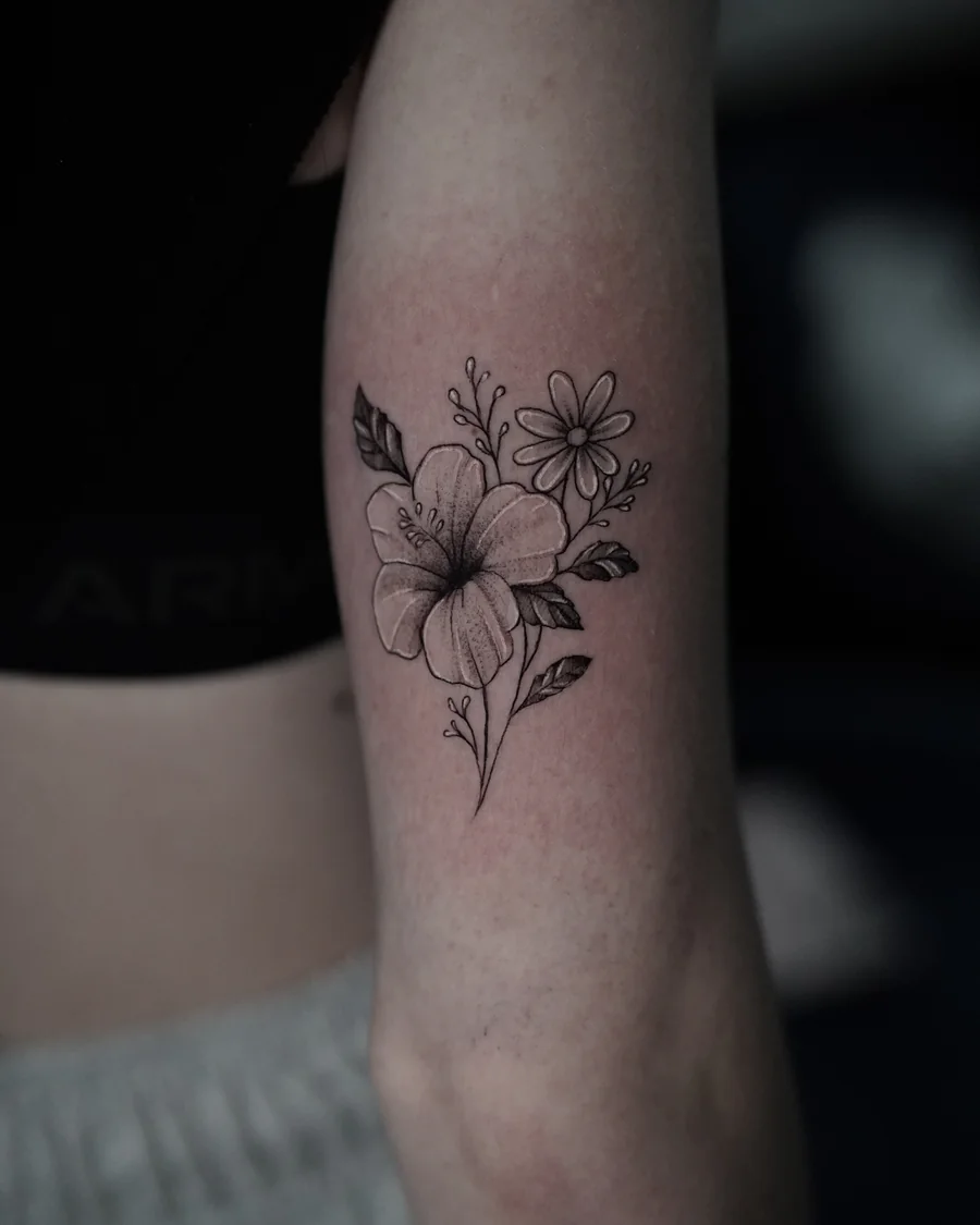 A small bouquet of sunflower-like blooms and leaves drawn in fine black lines on the forearm.