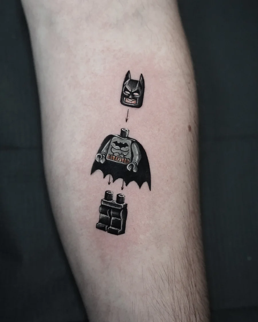 A small LEGO-style Batman tattoo with the mask, torso and legs separated vertically.
