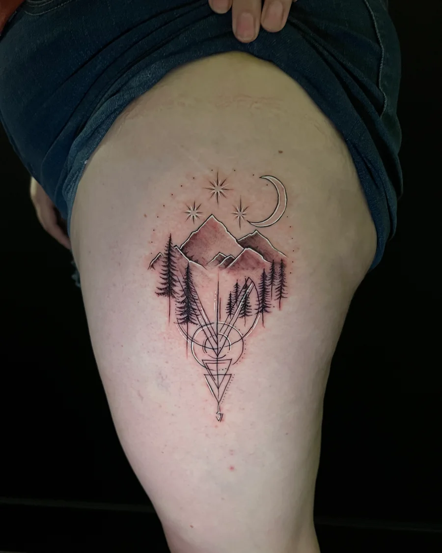 A geometric mountain and pine-tree tattoo with a crescent moon, small stars and pointed linework on the thigh.
