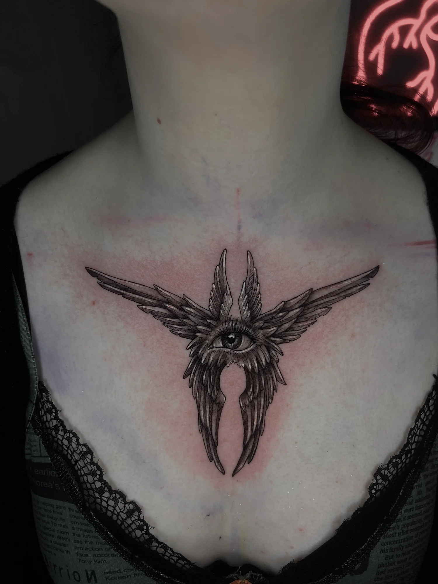 An ornamental eye with radiating feather-like wings and pointed forms across the upper chest.