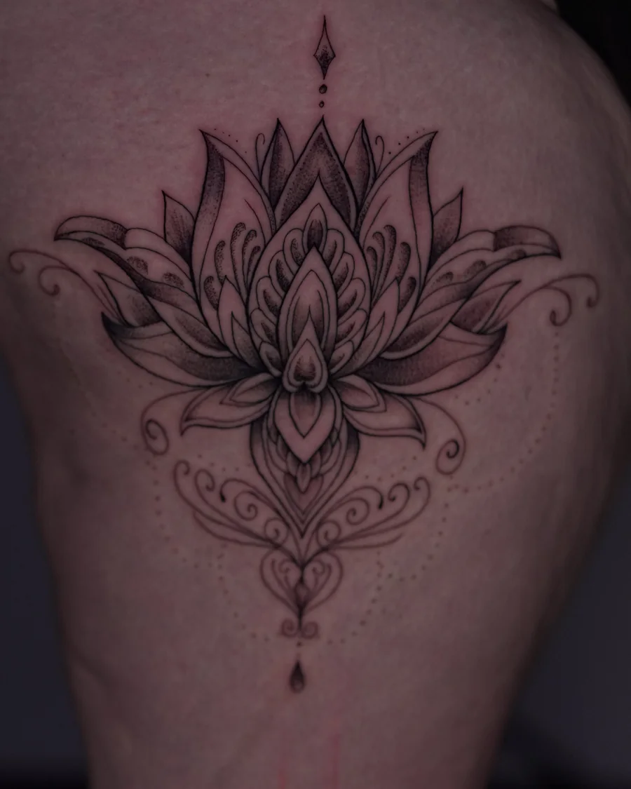 An ornamental lotus tattoo with layered petals, fine shading and symmetrical curved details.