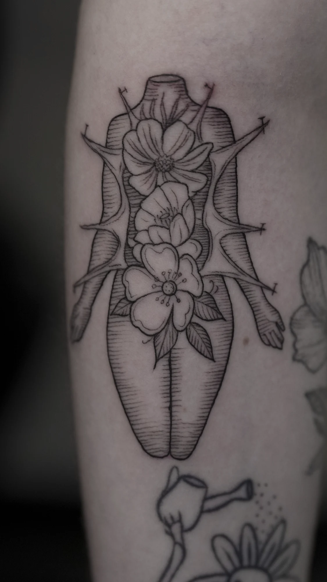 Fine-line flowers surrounded by a symmetrical pointed ornamental outline, with small curved details.