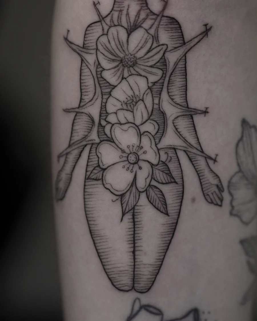 Fine-line flowers surrounded by a symmetrical pointed ornamental outline, with small curved details.