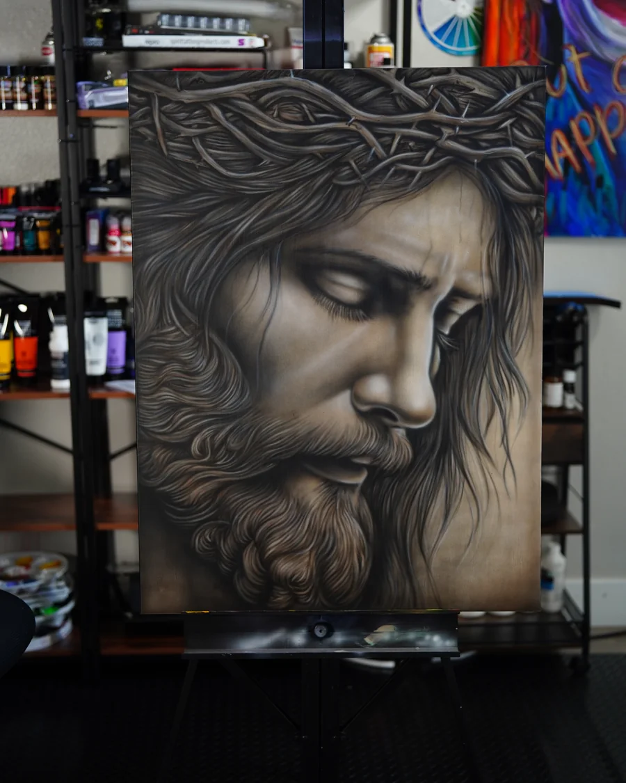 A monochrome painted portrait of Jesus wearing a crown of thorns, with his face lowered and eyes partly closed.