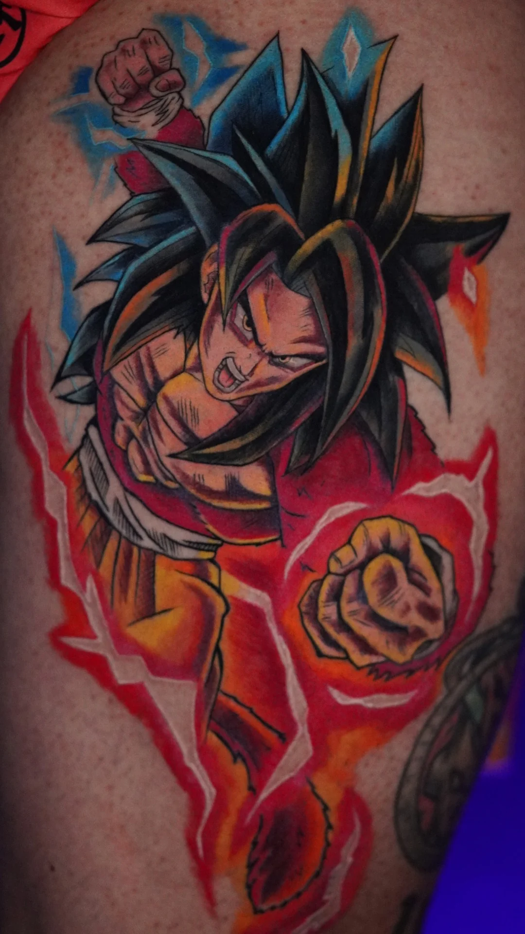 A brightly colored anime fighter with long spiked black hair, a red upper body and a yellow and red aura.