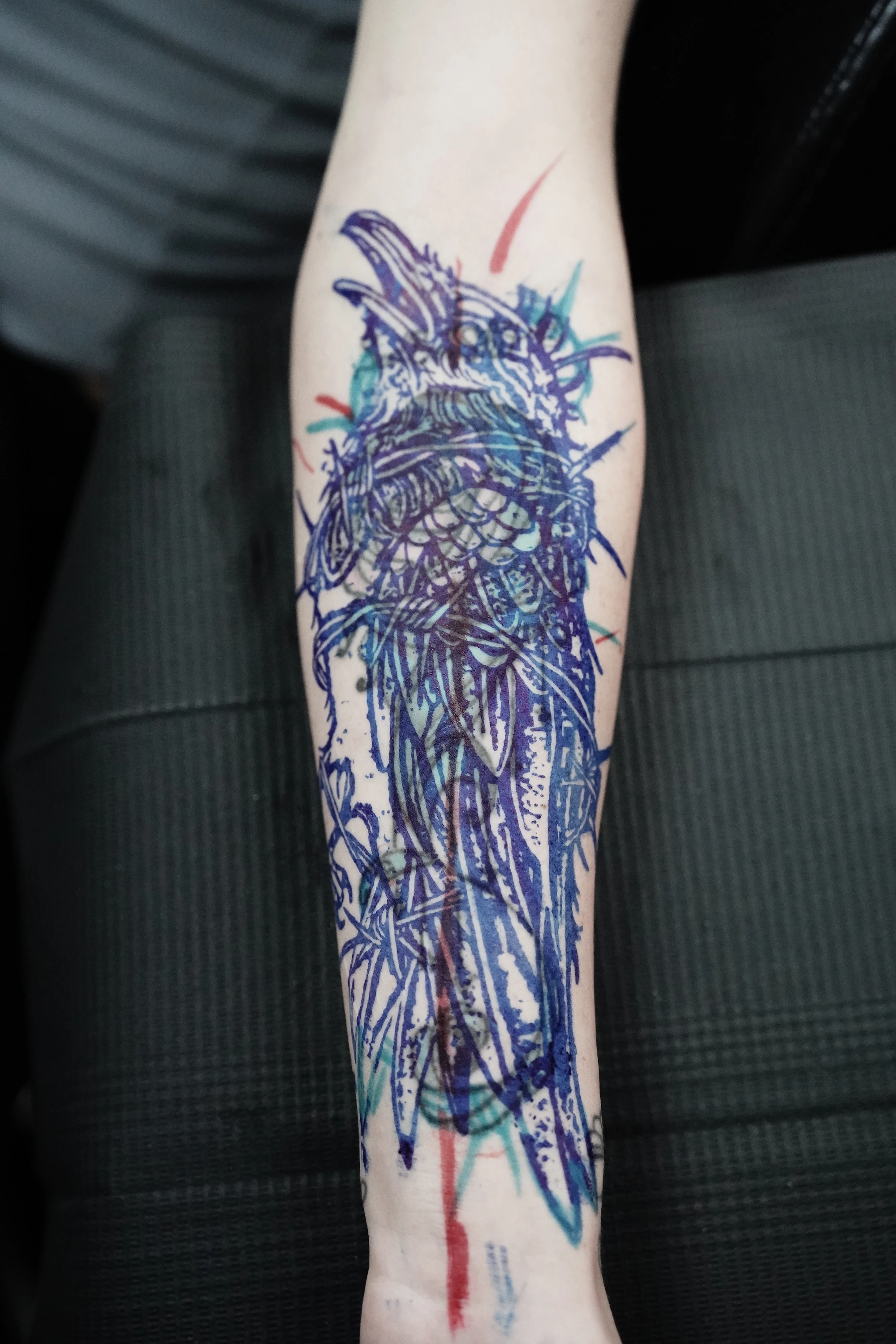 Raven stencil positioned over the earlier rose tattoo on the forearm.